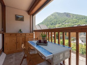 Un balcón con mesa y sillas de madera, una pequeña barra y vistas a la montaña.