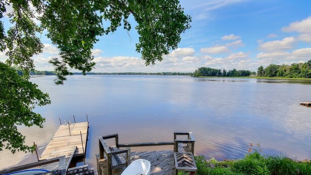 Une jetée en bois s’étendant sur un lac paisible, avec une baignoire blanche et un kayak sur la jetée.