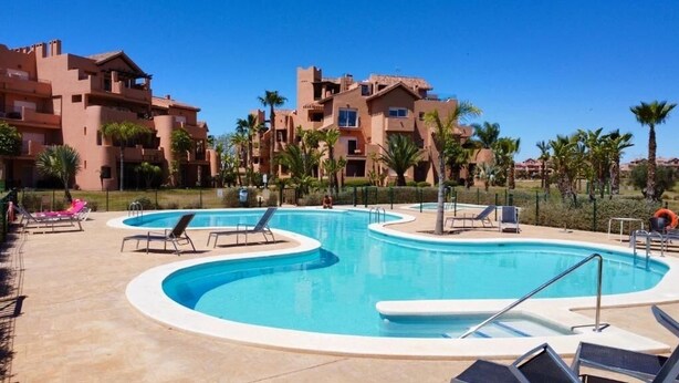 A swimming pool with lounge chairs and a building in the background.