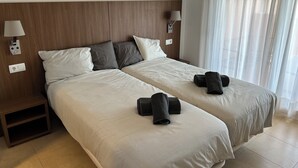 A double bed with two pillows, a nightstand, a lamp, and a window with curtains.