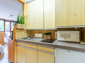 Une cuisine compacte avec des meubles en bois, un évier, un four à micro-ondes et un petit plan de travail.