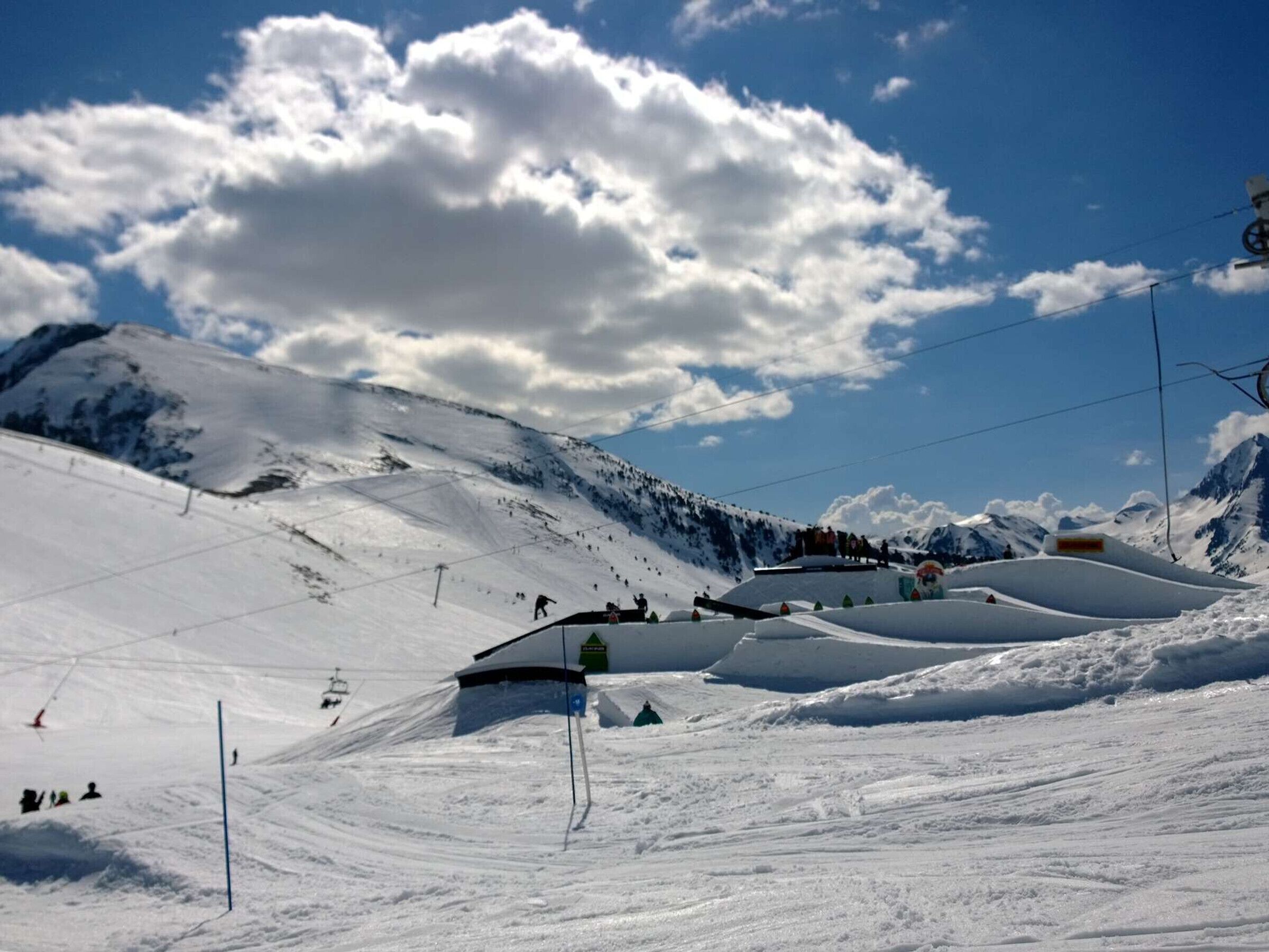 A snow-covered ski slope with a ski lift and a mountain backdrop.