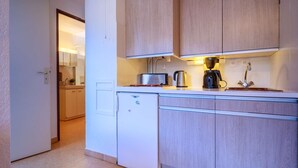 Cocina compacta con armarios de madera, lavavajillas integrado, cafetera y tostadora.