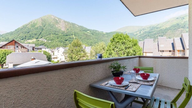 A balcony with a table set for two, chairs, and a potted plant. - 4-Person Apartment in Saint-Lary with Parking (Saint-Lary-Soulan)