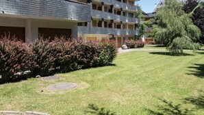 A multi-story hotel with balconies, a well-maintained lawn, and a variety of shrubs. - 4-Person Apartment in Saint-Lary with Parking (Saint-Lary-Soulan)