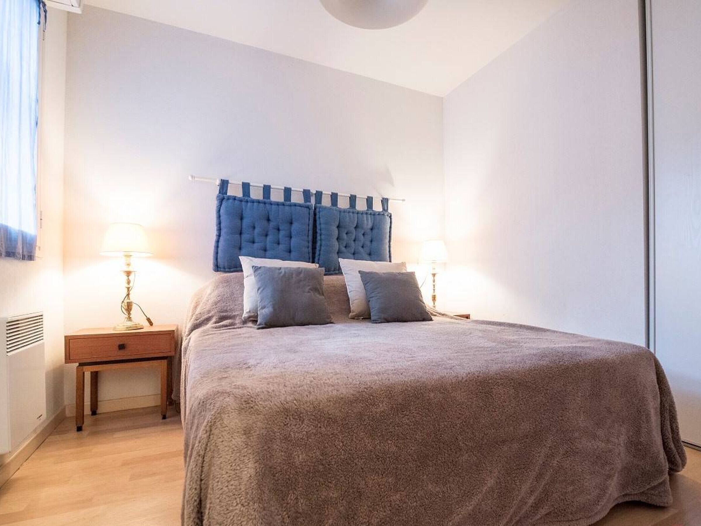 Un dormitorio con una cama grande, dos mesitas de noche y un cabecero.