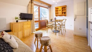 A cozy room with a wooden dining table, chairs, a TV, and a small cabinet. - Studio cabin for 4 people in Saint Lary Soulan with parking (Saint-Lary-Soulan)
