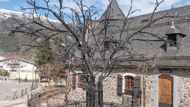 A stone building with a steep roof, a wooden door, and a metal fence. - Studio cabin for 4 people in Saint Lary Soulan with parking (Saint-Lary-Soulan)
