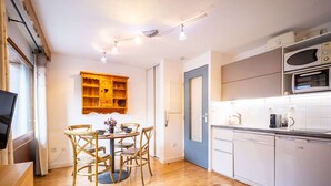 A compact kitchen with a dining area, wooden furniture, and a microwave. - Studio cabin for 4 people in Saint Lary Soulan with parking (Saint-Lary-Soulan)