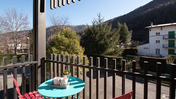 Un balcón con mesa y sillas, con vistas a un paisaje montañoso.