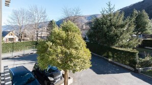 Una calle residencial con un coche aparcado, un árbol y casas al fondo.