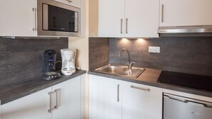 A compact kitchen with white cabinets, a built-in microwave, a coffee maker, a sink, and a dishwasher. - Apartment for 6 people close to ski slopes (Saint-Lary-Soulan)