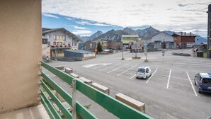 A parking lot with a white van and a blue van, surrounded by buildings and mountains. - Apartment for 6 people close to ski slopes (Saint-Lary-Soulan)