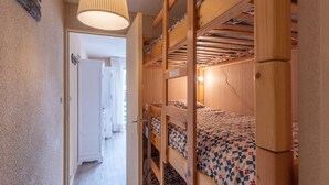 A dormitory room with bunk beds, a hanging lamp, and a door leading to another room. - Apartment for 6 people close to ski slopes (Saint-Lary-Soulan)