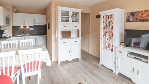 A compact kitchen with white cabinetry, a dining table with chairs, and a television on a cabinet. - Apartment for 6 people close to ski slopes (Saint-Lary-Soulan)