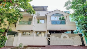 A two-story residential building with a white exterior, a gated entrance, and a covered driveway. - Butterfly Residency (Chennai)