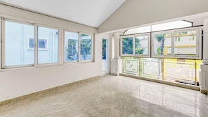 A spacious room with large windows, a marble floor, and a view of the outside. - Butterfly Residency (Chennai)