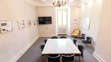A conference room with a large table, chairs, a TV, and framed pictures on the walls.