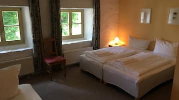 A room with two beds, a chair, a window, and a lamp.