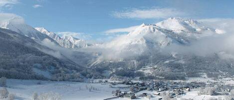 Un paisaje montañoso cubierto de nieve con un pequeño pueblo enclavado en el valle.