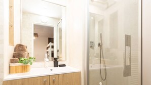 A modern bathroom with a wooden vanity, a glass shower enclosure, and a mirror above the sink. - Charming T3 in central Saint Lary Soulan for 11 people (Saint-Lary-Soulan)