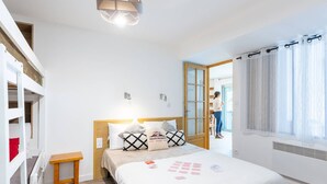 A bedroom with a bed, bedside table, and a window with curtains. - Charming T3 in central Saint Lary Soulan for 11 people (Saint-Lary-Soulan)