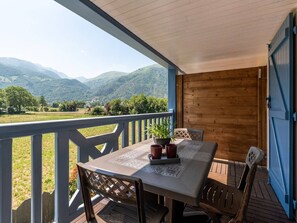 Un espace extérieur abrité, avec une table et des chaises, offrant une vue sur un paysage montagneux.