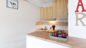 Een keuken met houten kastjes, een aanrecht, een spoelbak en een barbord.