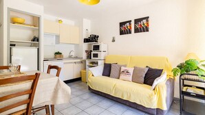 A compact living space with a dining table, a sofa, a kitchen area, and a small balcony.