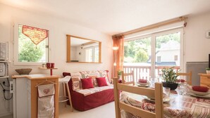 Ein gemütliches Zimmer mit Bett, Schreibtisch, Stuhl, Esstisch und Fenster.