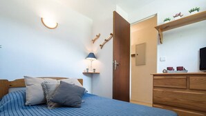 Ein Schlafzimmer mit Bett, Nachttisch, Lampe, Kommode und Fernseher.