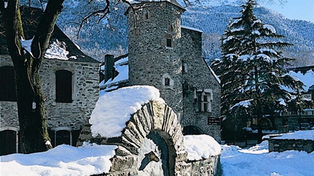 Ein Steinhaus mit einem verschneiten Bogen und einem kleinen Turm.