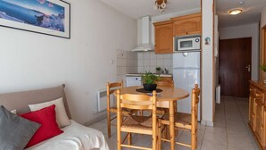A compact living space with a dining area, kitchenette, and a sofa with cushions.