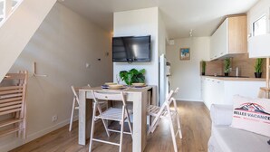 A compact living space with a dining area, kitchenette, and a staircase.