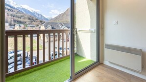 A balcony with a view of mountains and a parking area.