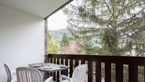 Un balcón con mesa y sillas, con vistas a un área boscosa y colinas.