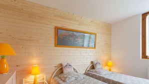 Una habitación con dos camas, una pared de madera, un cuadro y una ventana.