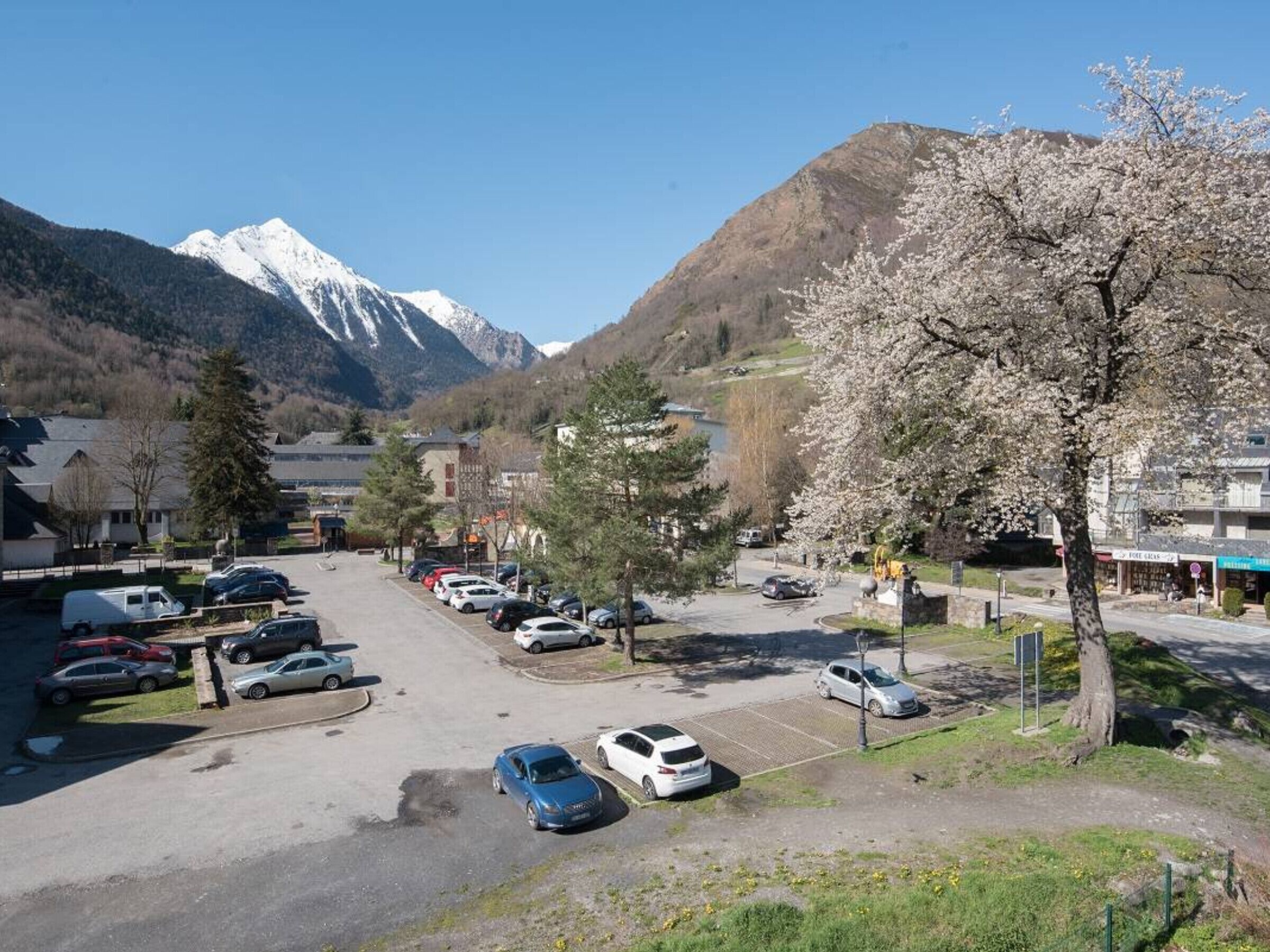 Un estacionamiento con coches, un edificio con un letrero y montañas al fondo.