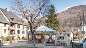 Un edificio europeo tradicional con balcón, un carrusel y un pequeño quiosco.