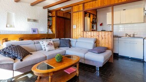 Un salon chaleureux avec un canapé, une table basse en bois et une cuisine dotée de meubles blancs.