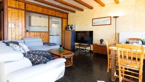 Un salon confortable avec un canapé, une table basse, un téléviseur et un coin repas comprenant une table et des chaises.