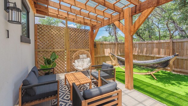 Un patio techado con muebles de madera, una hamaca y un cerramiento de celosía.