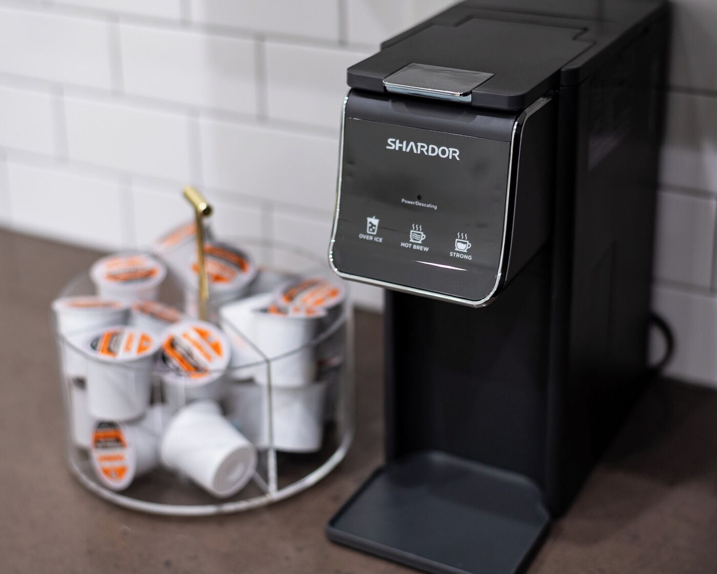 En kaffemaskin med en kontrollpanel märkt med "SHARDOR" och följande alternativ: "Ström: avkalkning", "För servering med is", "Varmt kaffe" och "Starkt kaffe".