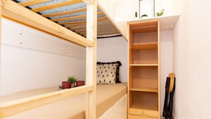 Ein kompakter Raum mit Etagenbett, einer kleinen Sitzecke und einem eingebauten Kleiderschrank.