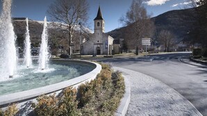 Eine Kirche mit einem Glockenturm, einem Brunnen und einer gepflasterten Straße mit Bürgersteig.