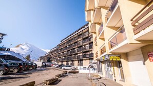 A multi-story hotel with balconies, a ski resort sign, and a mountain in the background. - Cozy studio 6 pers. ski-in/ski-out (Saint-Lary-Soulan)