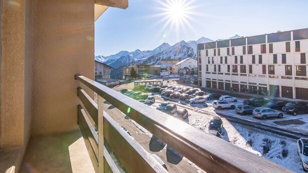 A balcony with a view of a parking lot and buildings, including a bus stop and a building with a sign that reads "Hotel". - Cozy studio 6 pers. ski-in/ski-out (Saint-Lary-Soulan)
