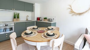 A modern kitchen with a round dining table, white chairs, and a built-in oven.