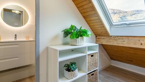 A modern bathroom with a skylight, white cabinetry, and a potted plant.