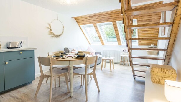 A cozy kitchen with a dining table set for four, a blue cabinet, and a wooden ladder.